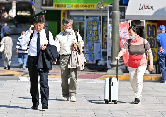 上着を脱いだり腕まくりをしたりして歩く人たち＝19日午後２時15分、宇都宮市大通り３丁目