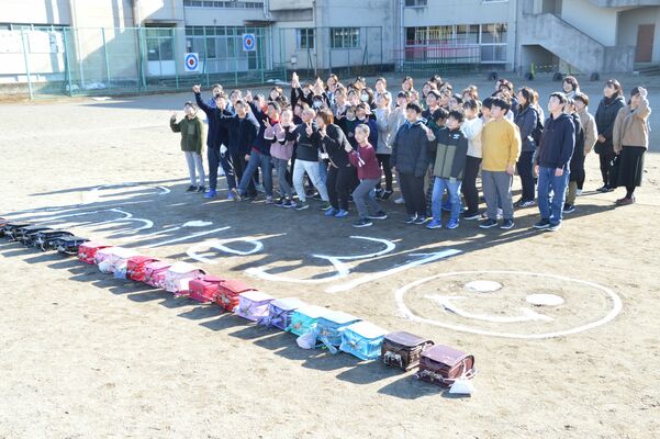 ドローンに向かってポーズを取る児童と保護者