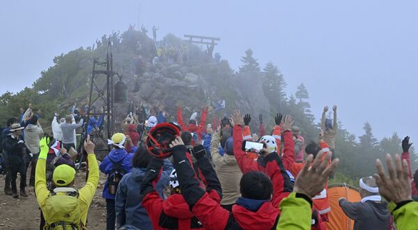 霧に覆われた山頂で、御来光の方向を見て万歳する登山者ら＝１日午前４時55分、男体山山頂