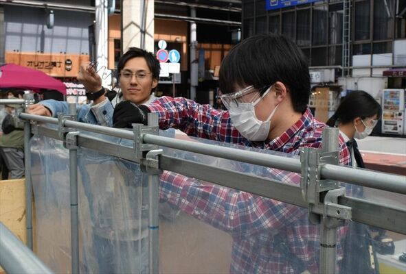 業用ビニールハウスのシート貼りを体験する来場者（右）
