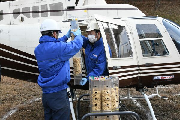 散布するワクチンをヘリコプターに運び込む作業員＝２８日午前、日光市藤原