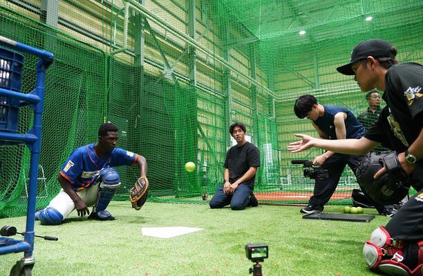 捕手の技術指導を受けるデニス選手（左）