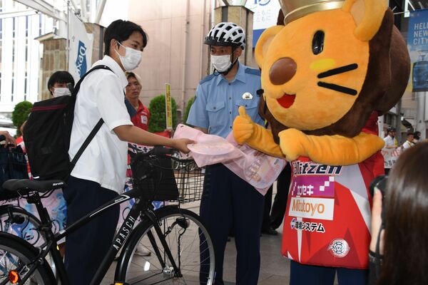 警察官から啓発グッズを受け取る自転車利用者＝１日朝、宇都宮市江野町