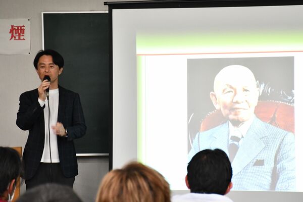 古関裕而のスライドを前に活動実績を紹介する西形さん