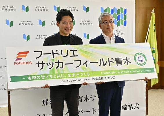 愛称が書かれたプレートを持つ渡辺市長（左）と内田社長