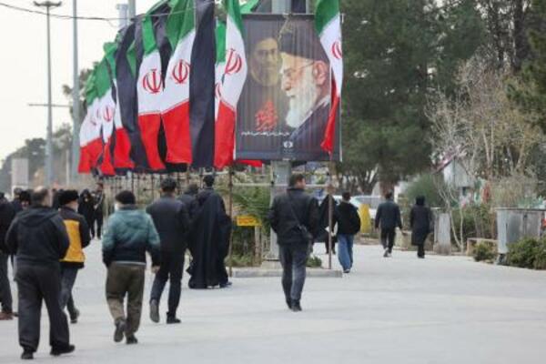 　９日、イラン・テヘランで、国旗や殺害されたハメネイ師のポスターが掲げられた通りを歩く人（ＷＡＮＡ提供・ロイター＝共同）