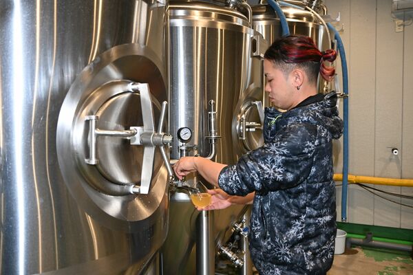 タンクから「世界を旅するカントリービール」を抽出する小野崎さん＝小山市