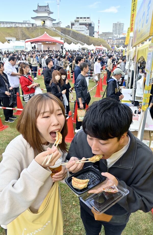 名店の味を食べ歩く来場者=1日午前11時10分、宇都宮市本丸町