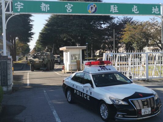 自衛隊の車両を先導して宇都宮駐屯地から出るパトカー＝２日午後１時30分、宇都宮市茂原１丁目