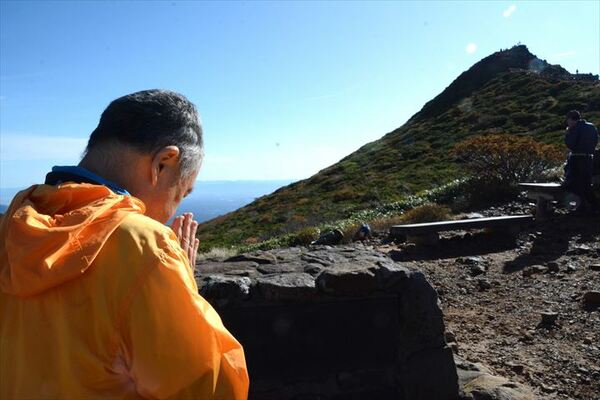 亡くなった４人を悼み、登山道で手を合わせる登山者。正面には朝日岳が見える＝８日午前８時15分、那須町湯本