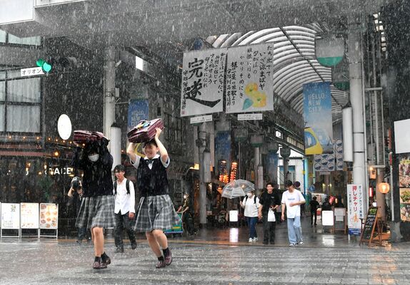 突然の大雨に見舞われて傘を持たずに交差点を渡る高校生ら＝26日午後5時25分、宇都宮市江野町