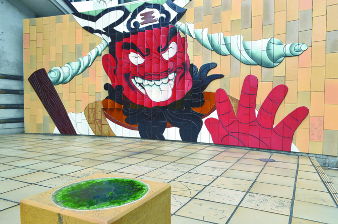 七つの伝統釉で彩られた西明寺の「笑い閻魔（えんま）」の陶板アート（益子駅前）