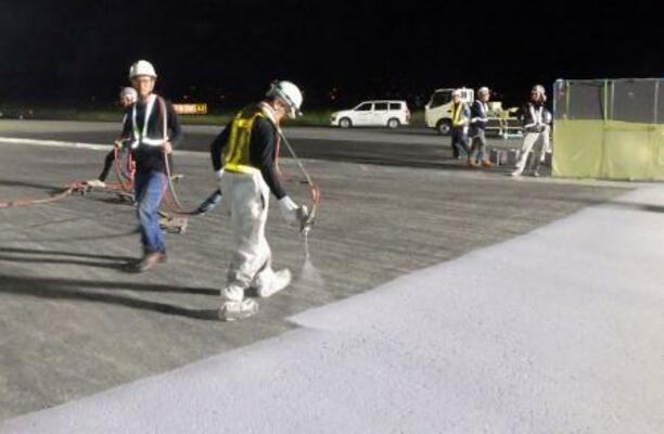 　滑走路の誘導路を舗装する作業員＝７日未明、成田空港（ＮＡＡ提供）