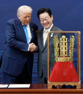 韓国・慶州で、トランプ米大統領(左)に「天馬塚金冠」のレプリカを贈呈し握手する李在明大統領=29日(聯合=共同)