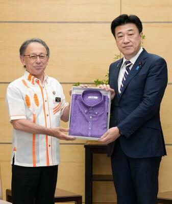 沖縄県の玉城デニー知事(左)から「かりゆしウエア」を贈呈される木原官房長官=22日午前、首相官邸