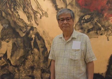 　「沖縄戦の図」の前に立つ佐喜眞道夫さん