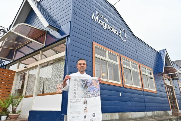 店頭で開店記念イベントのポスターを手にする河又さん