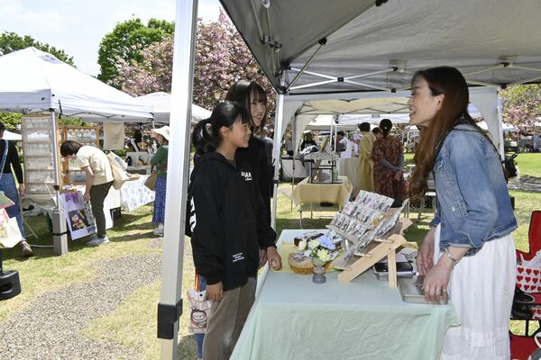 満開の桜の下、買い物などを楽しむ来場者