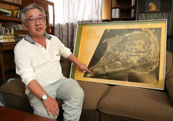 硫黄島の航空写真を前に、鶴次さんを振り返る茂之さん＝４月下旬、足利市