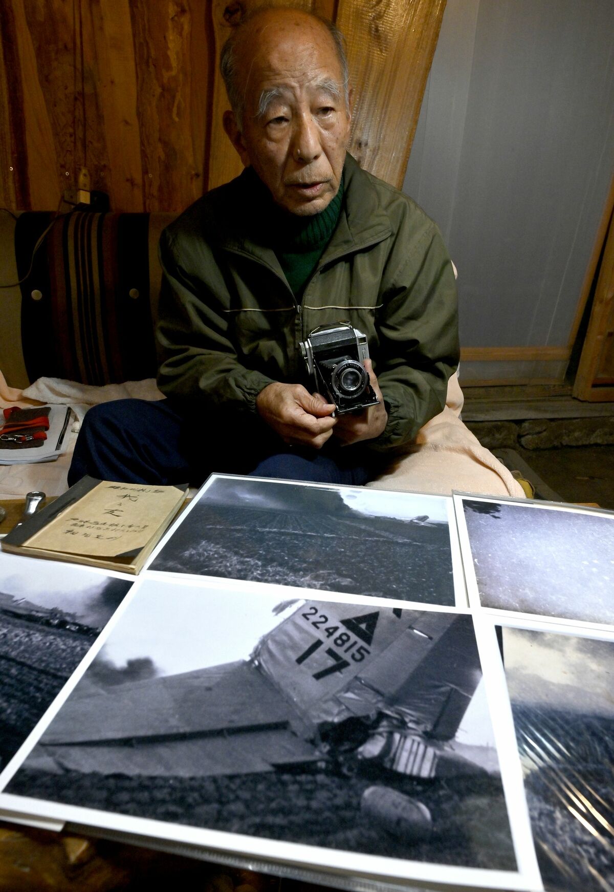 父定利さんが撮影したB29墜落直後の写真や使用したカメラを手に当時の戦禍に思いをはせる相場さん=2024年12月19日午後3時、群馬県邑楽町藤川