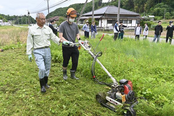 草刈り機の扱いを学ぶ学生