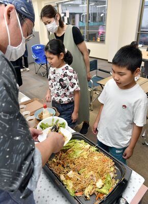 焼きそばの盛り付けに見入る子どもたち＝10日午後６時20分、宇都宮市曲師町