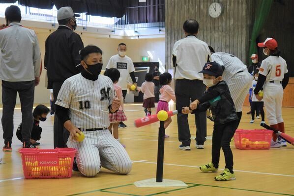 ティーを使った打撃練習をサポートする澤井さん（手前左）