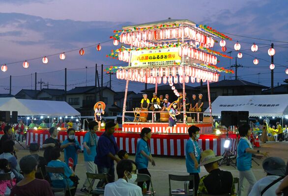 やぐらの周りを回りながら八木節を踊る出演者ら