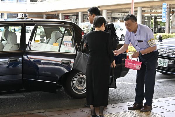 新運賃を周知するポケットティッシュをタクシー利用者に手渡す君島会長(右)=22日午前、JR宇都宮駅