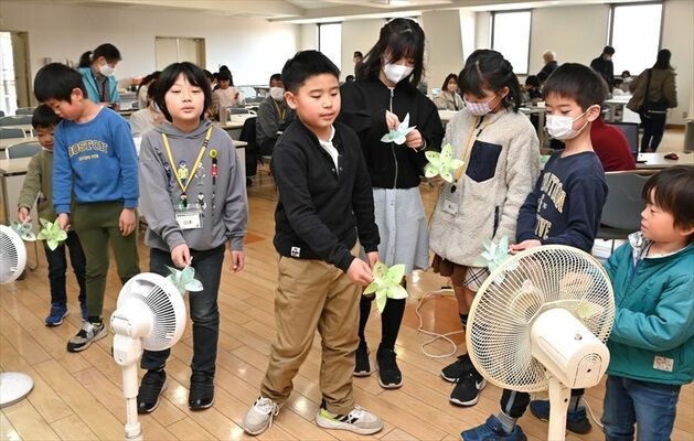 作ったばかりの風車を扇風機に当てて回す子どもたち