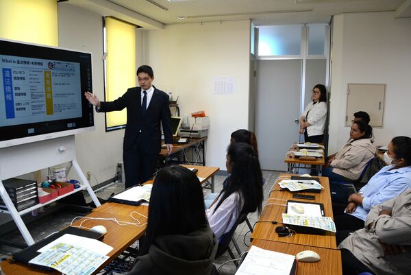 外国人留学生にサイバーパトロールの説明を行う県警の担当者(左)=9日午前9時45分、宇都宮市鶴田町