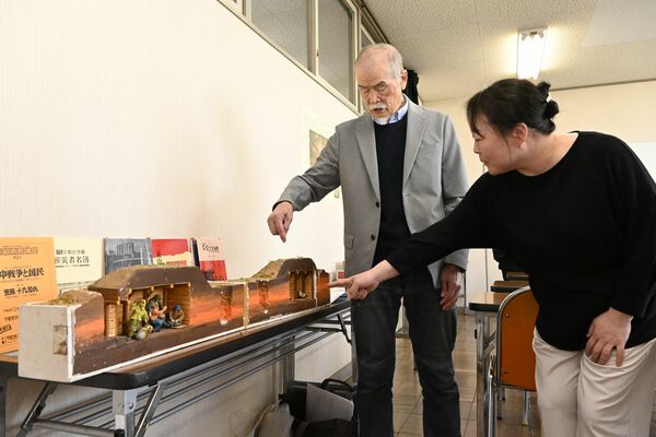 県立博物館に引き継ぐ防空壕の模型を小栁特別研究員（右）に説明する田中代表＝24日午前、宇都宮市中央１丁目