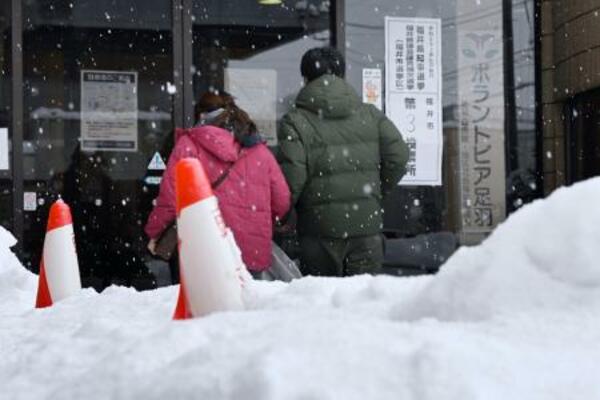 雪が積もる中、福井県知事選の投票所に向かう人たち=25日午後、福井市