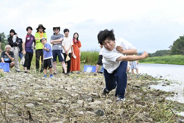 力強く石を投げる参加者