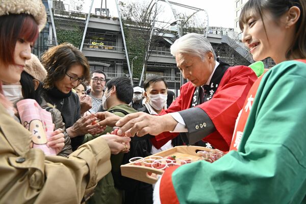 来場者にイチゴを手渡す福田知事（右から２人目）＝16日午後、東京都渋谷区