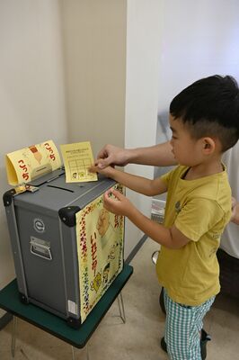 投票用紙を投票箱に入れる子ども