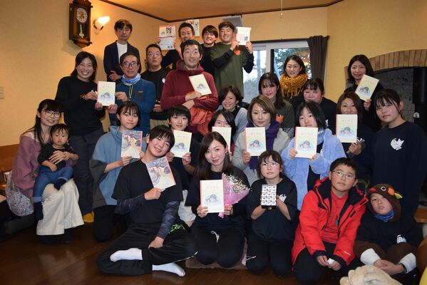 絵本の完成を喜ぶキリフリ自然学校参加者と小笠原さん（前列左から２番目）＝１２月、日光市内