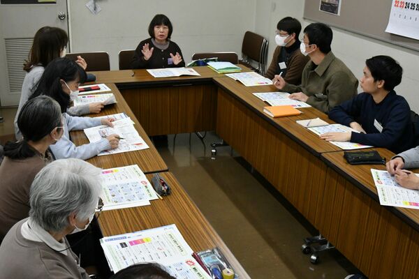 平易な日本語で記した防災マニュアルを題材に、外国人らに災害対応の大切さを伝える清原地区国際交流会の阿久津さん（中央奥）＝２月下旬、宇都宮市清原工業団地