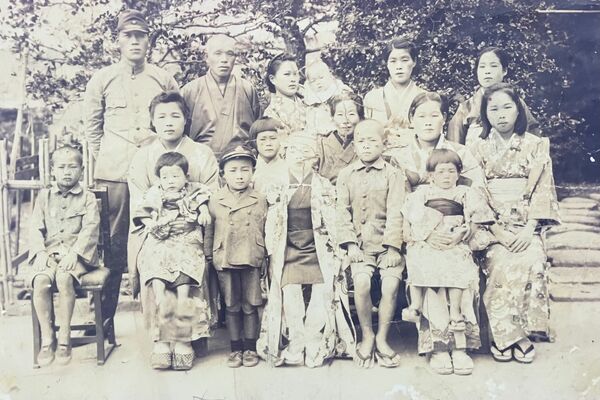 美馬さんの母の実家に残っていた写真。中央に立つ少年の後ろの少女が美馬さん。妹を抱っこする母（前列右から２人目）、兄（前列右から３人目）らが写る。母は弟を妊娠中だった＝１９４４年撮影