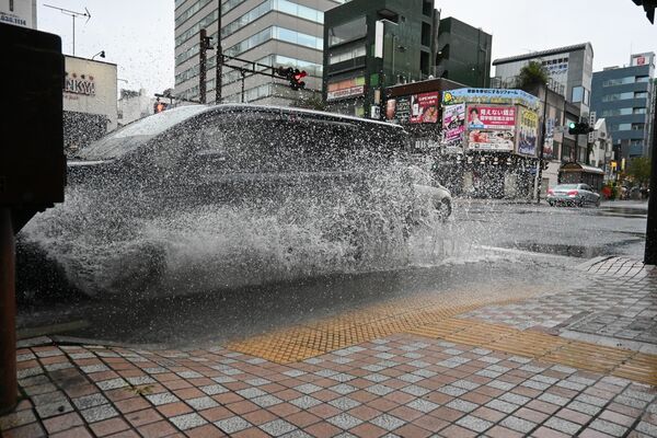 水しぶきを上げて走行する車、宇都宮市の本町交差点