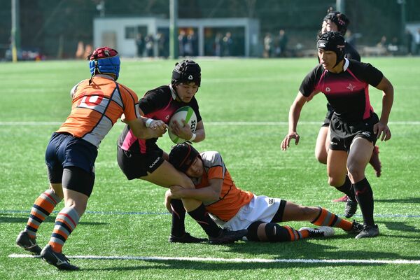 後半20分、佐野日大のＳＯ遠藤（中央）が相手のタックルを受けながら攻め上がる＝国学栃木高ラグビー場