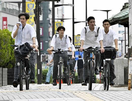 うだるような暑さの中、汗を拭いながら走行する学生たち＝17日午後１時40分、宇都宮市馬場通り４丁目