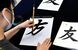 左手で筆を持つ場合、半紙を少し斜めに、筆置きは左、手本は右に置く工夫があると書きやすい＝７月末、松山市文京町の愛媛大