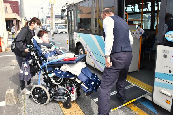 運転手（右）が設置したスロープでバスに乗り込む稲生さん（中央）とヘルパー＝３月中旬、宇都宮市