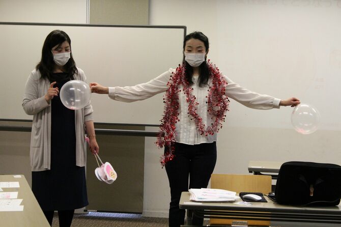 風船や飾りを使って子宮や生理の仕組みを説明する柚木さん（左）