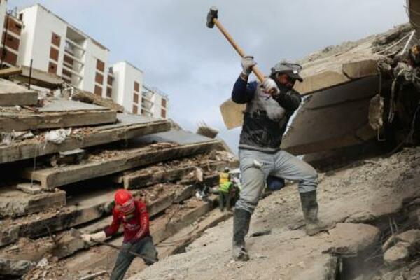 10日、地震で倒壊した建物のがれきの上で活動する救助隊員=ベネズエラ・ラグアイラ州(ロイター=共同)