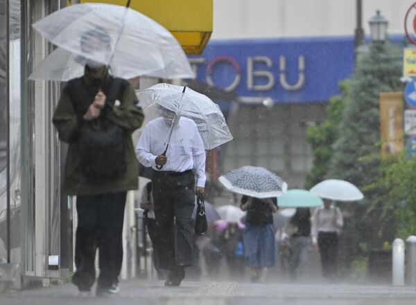 強い雨の中、傘を差して歩く人たち＝３日午前８時、宇都宮市池上町、加藤竜矢撮影