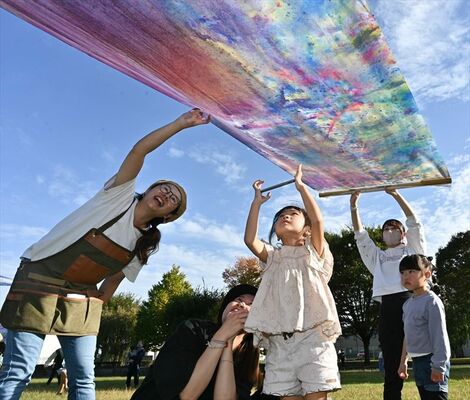 青空の下、絵の具を混ぜて作った色を観察する子どもたち