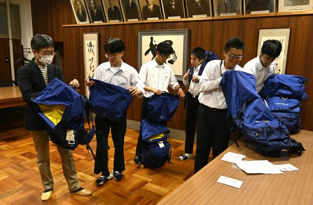 浅井さん（左）が寄贈したザックを開けて中を確かめる大田原高山岳部の生徒ら＝１５日午後、大田原市紫塚３丁目