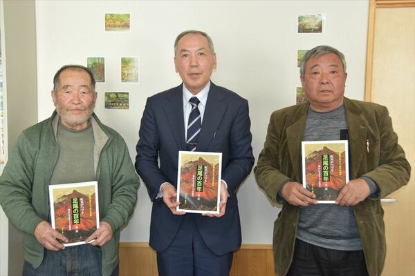 市教委に寄贈した本を手にする、（右から）藤井さん、斎藤教育長、石川さん